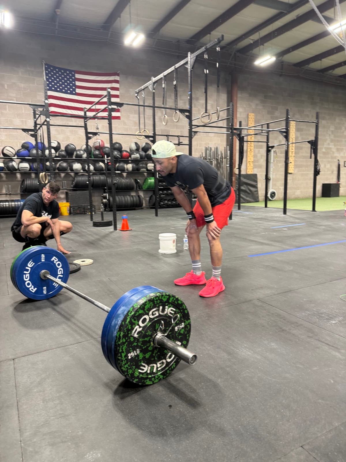 A coach watching a member set up a barbell at CrossFit Albuquerque