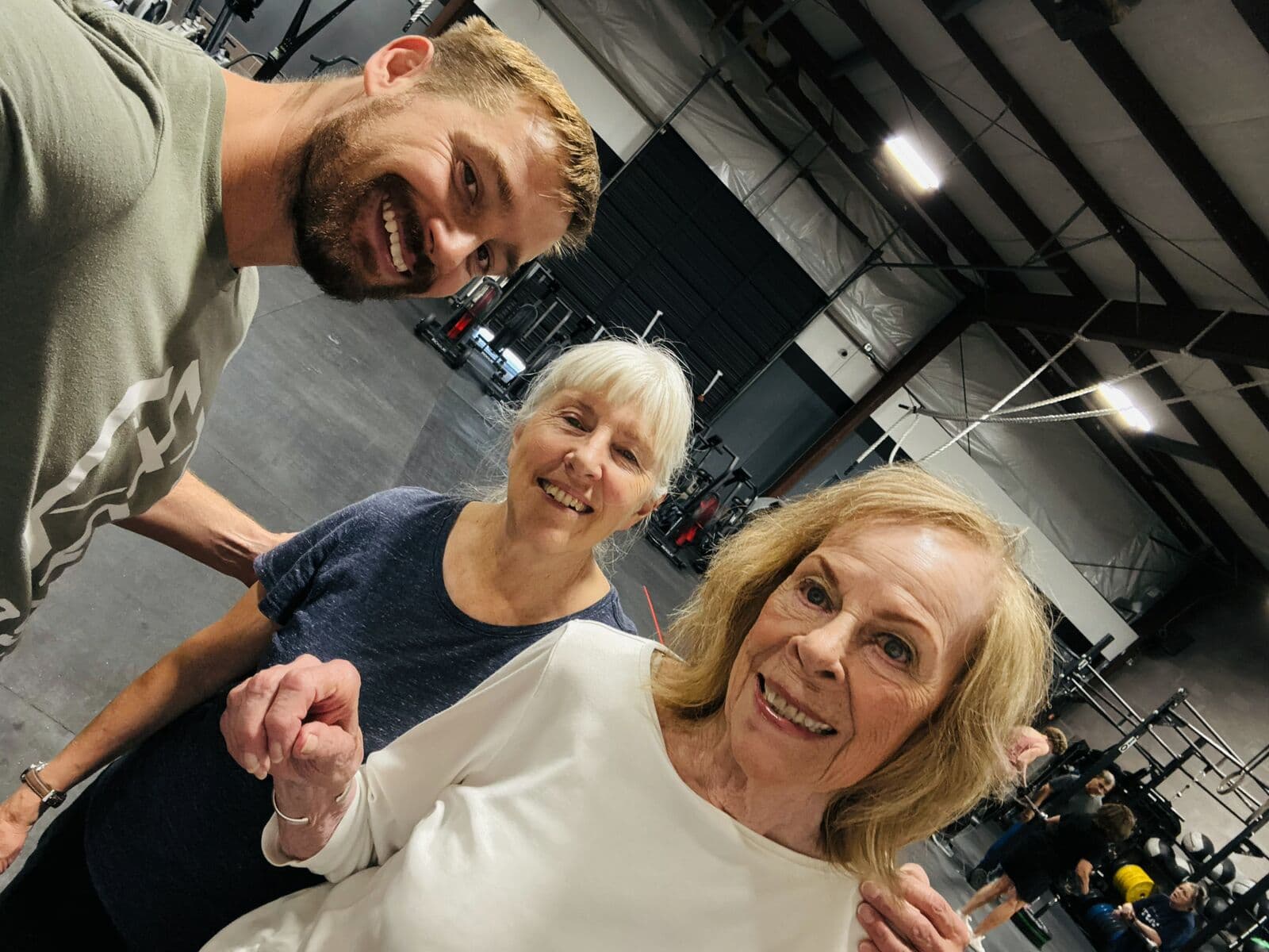A coach and two members taking a selfie on the gym floor