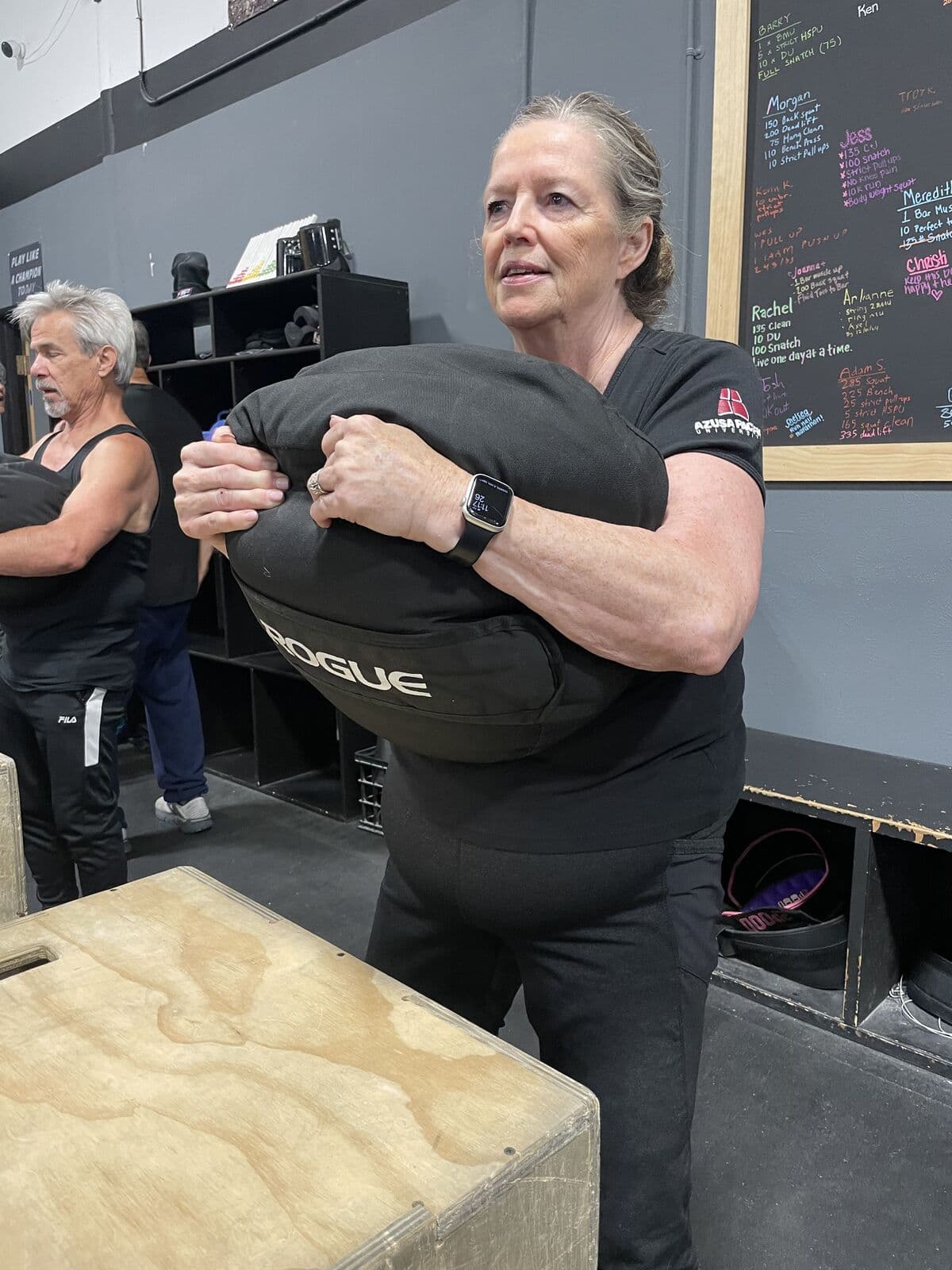 A Fit for Life member carrying a sandbag across the gym floor