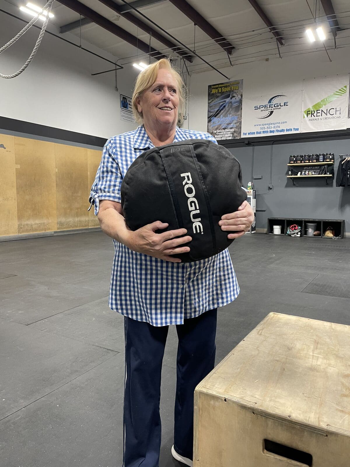 A Fit for Life member holding a sandbag and smiling