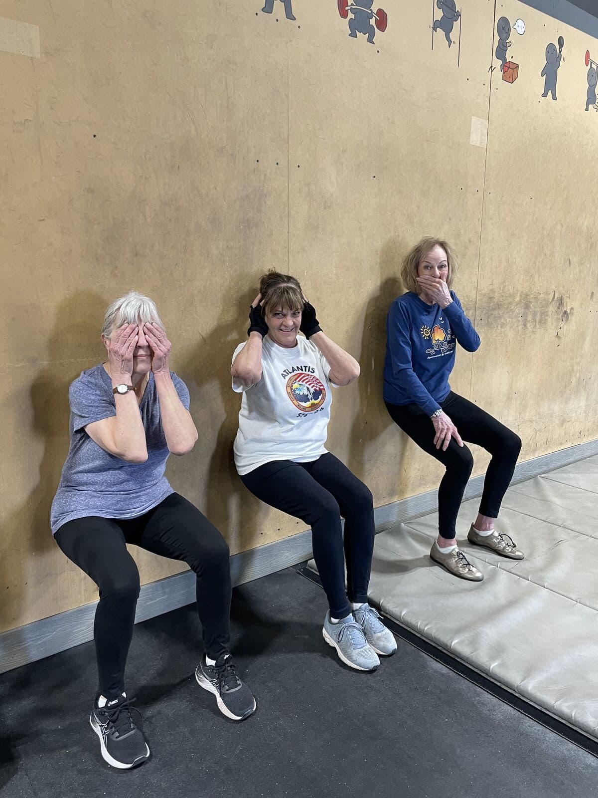 Three Fit for Life members holding a wall sit and laughing at CrossFit Albuquerque